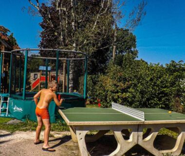 Aire de jeux extérieure avec table de ping-pong et enfants au Camping Plein Soleil