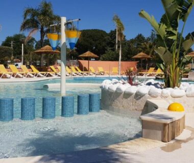 Piscine avec toboggan transats et palmiers au Camping Rêve des Iles