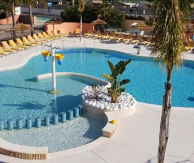 Piscine extérieure avec transats et palmiers au Camping Rêve des Iles