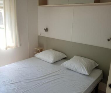Chambre avec lit double fenêtre et rangements au CAMPING RÊVE DES ILES