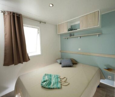 Chambre avec lit double et fenêtre dans le mobil-home du CAMPING U SOMMALU