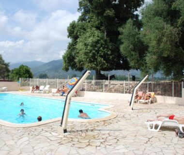 Piscine extérieure avec chaises longues et arbres en arrière-plan au camping U Sommalu