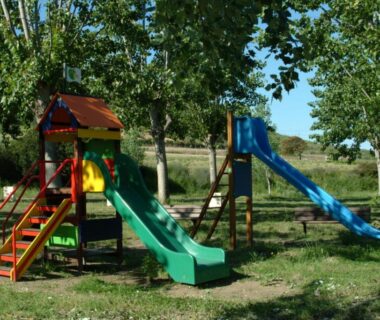 Aire de jeux avec toboggans sous les arbres au camping U Sommalu