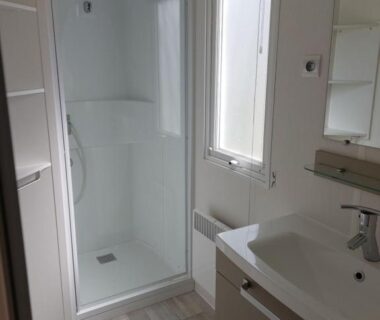 Salle de bain avec cabine de douche lavabo et fenêtre dans le CARNAC Mobil-Home Camping 4 étoiles