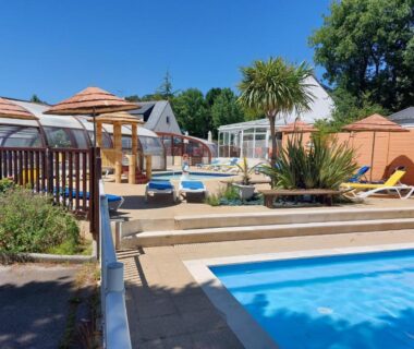 Piscine extérieure avec transats et palmiers au CARNAC Mobil-Home Camping 4 étoiles
