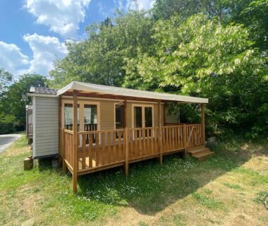 Extérieur avec terrasse couverte et mobil-home entouré d'arbres au C&B Lodges
