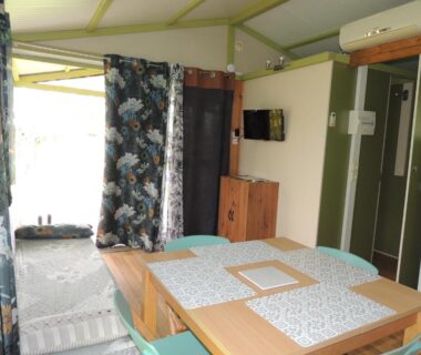 Intérieur du chalet avec table à manger et télévision du CHALET 4 personnes maxi tout confort location en gîte