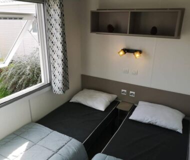 Chambre avec deux lits simples et fenêtre dans le mobile home Chez Lolo