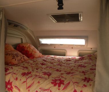 Intérieur avec lit et hublot dans le camping car CHEZ MITCH EN CAMPING CAR et grand espace extérieur