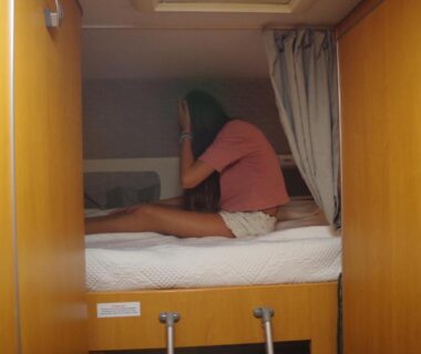 Cabine lit dans camping car avec personne assise chez Mitch en camping car et grand espace extérieur
