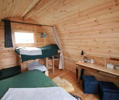 Intérieur en bois avec deux lits et un bureau dans la Cabane Les Pourettes