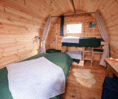 Intérieur en bois avec lits et fenêtre dans la Cabane Les Pourettes