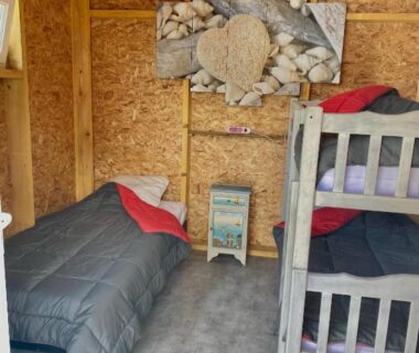 Intérieur de cabane en bois avec lits superposés et lit simple dans la Cabane Randonneurs