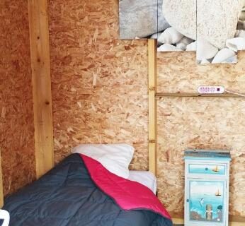 Intérieur en bois avec lit simple et étagères décoratives dans la Cabane Randonneurs