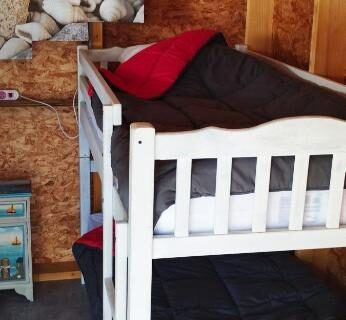 Intérieur de la cabane avec lits superposés, coussin rouge et décoration marine dans la Cabane Randonneurs