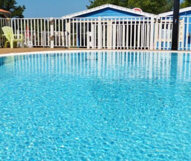 Piscine extérieure avec cabanes colorées et transats au camping Cabane Randonneurs