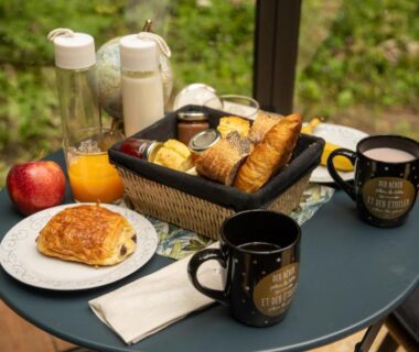Terrasse avec petit déjeuner de viennoiseries jus et tasses dans la Cabane insolite avec escape game