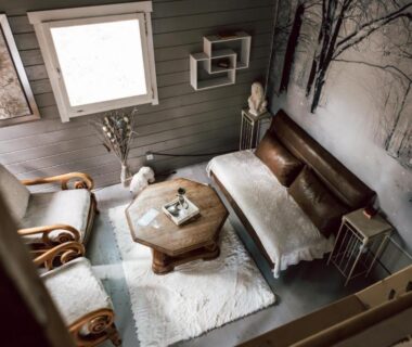 Intérieur salon rustique avec canapé fauteuils et table basse dans la Cabane insolite avec escape game