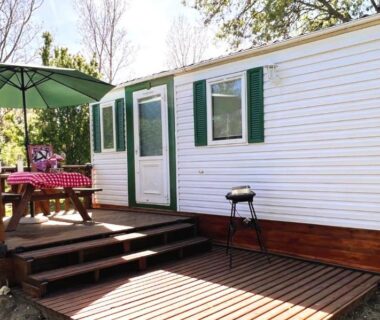 Terrasse en bois avec parasol et table du mobil‑home Cabane la Clef des Champs au Mas des Entrages