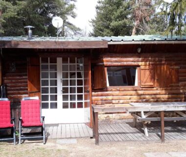 Façade de cabane en bois avec terrasse et chaises au camping Cabane randonneur
