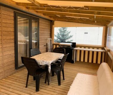 Terrasse couverte avec table chaises barbecue et banquette du camping Calme & Sérénité