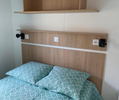 Chambre avec lit et étagère en bois dans le camping Calme & Sérénité