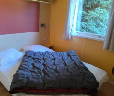 Chambre avec deux lits et fenêtre sur arbres du Camping 3 étoiles – Piscine – ccbfeif