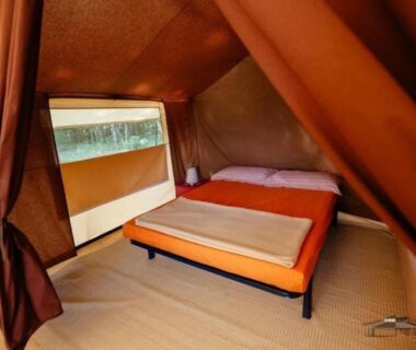 Intérieur de tente avec lit et fenêtre dans le Camping 3 étoiles Piscine chauffée Périgord Vert