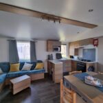 Séjour avec canapé d'angle et kitchenette dans le Camping 4* 3 CH 2 SDB- Lave linge- Lave vaisselle