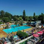 Piscine extérieure avec toboggans et parasols au Camping 4 étoiles - Parc aquatique - ccbbiei