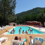 Piscine extérieure entourée d'arbres et transats au Camping 4 étoiles - Piscine - ccbbihi