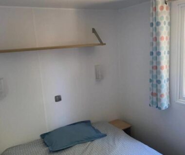 Chambre avec lit côté fenêtre et étagère dans le Camping 4 étoiles Piscine ccbbihi