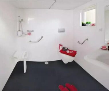 Salle de bains accessible avec barres siège et toilettes rouges dans le Camping 4 étoiles - Piscine - eed0fi