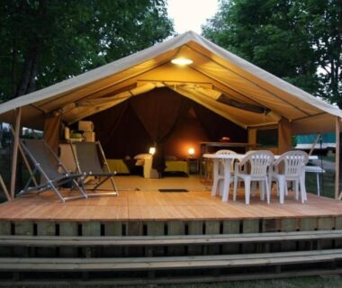 Terrasse en bois avec tente lodge éclairée et chaises au Camping 4 étoiles Piscine eed0fi