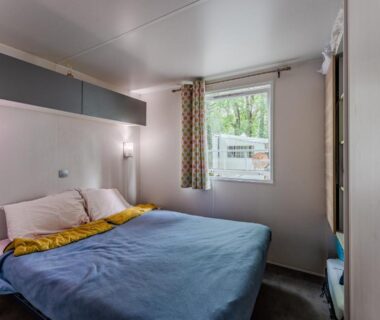 Mobil-home chambre avec lit double et fenêtre donnant sur l'extérieur au Camping 4 étoiles parc aquatique