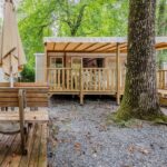 Terrasse couverte et table en bois sous les chênes du Camping 4 étoiles parc aquatique