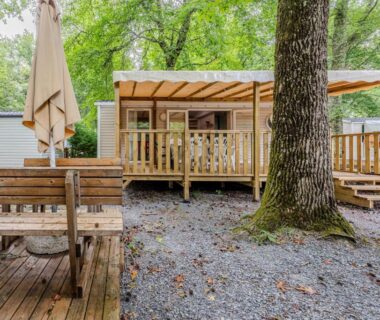 Terrasse couverte et table en bois sous les chênes du Camping 4 étoiles parc aquatique