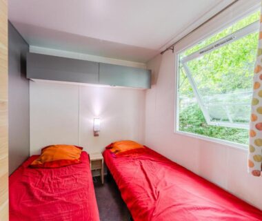 Intérieur de chambre avec deux lits simples et fenêtre au Camping 4 étoiles parc aquatique
