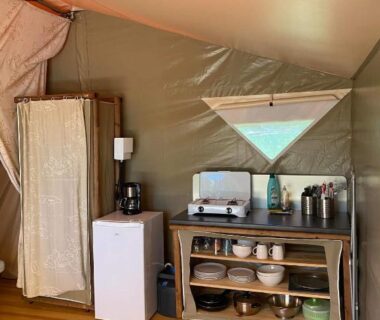 Intérieur de tente avec kitchenette frigo et rangements au Camping 46 Rainettes