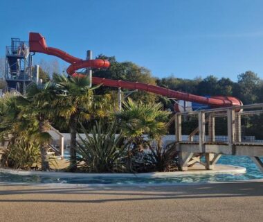 Piscine extérieure avec toboggans et palmiers au Camping 5 étoiles piscines chauffées club enfants mobilhome premium 6pers