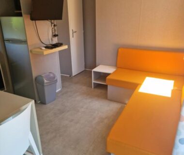 Intérieur mobilhome banquette orange télévision climatisation coin cuisine au Camping 5 étoiles piscines chauffées club enfants mobilhome premium 6pers