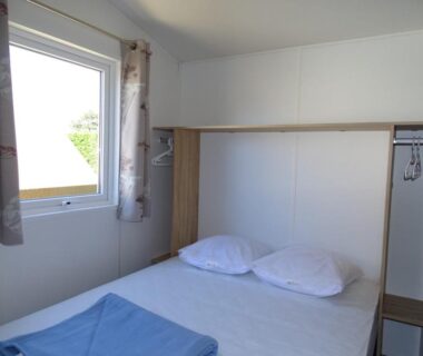 Chambre avec lit et fenêtre dans le locatif au Camping A l'Abri de l'Océan
