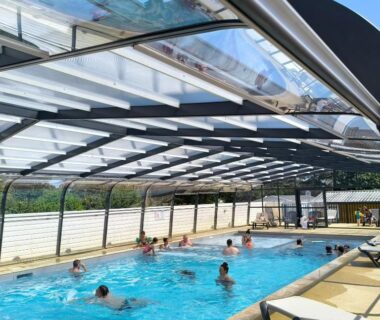 Piscine couverte avec baigneurs et chaises longues au camping A l'Abri de l'Océan
