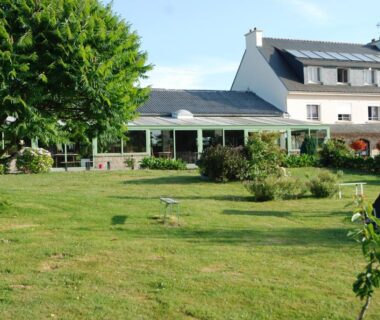 Pelouse et terrasse avec bâtiment en arrière plan au Camping A l'Abri de l'Océan