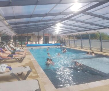 Piscine couverte avec baigneurs et transats au Camping A l'Abri de l'Océan