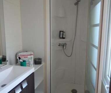 Salle de bain avec cabine de douche et lavabo au Camping A l'Ombre des Tilleuls