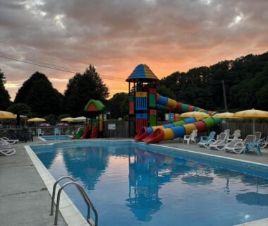 Piscine extérieure avec toboggans et transats au Camping A l'Ombre des Tilleuls