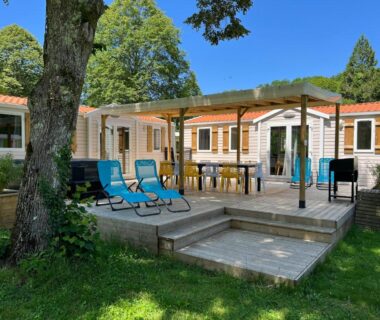 Terrasse en bois avec transats et table sous pergola au camping À l'Ombre des Tilleuls