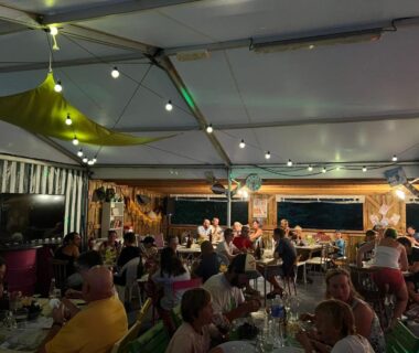 Terrasse couverte avec guirlandes et convives au Camping A l'Ombre des Tilleuls