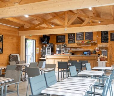 Salle commune avec comptoir bar et tables au Camping Abijune d'Étretat